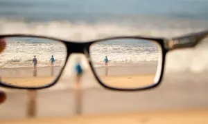 Okulary korygujące widzenie na plaży z dwojgiem dzieci w tle.