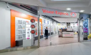 Sklep Vision Express z ekspozycją okularów i kobietą przeglądającą ofertę.