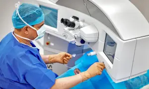Chirurg w masce i fartuchu operacyjnym obsługuje laser do korekcji wzroku.