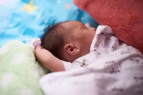 Śpiące dziecko, jak widzi 3 miesięczne dziecko: rozmyte kształty, jasne kolory, miękkie koce i pluszaki.