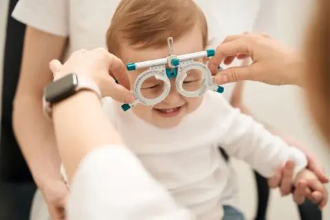 Uśmiechnięte niemowlę z oprawką optometryczną na nosie, jak widzi miesięczne dziecko.