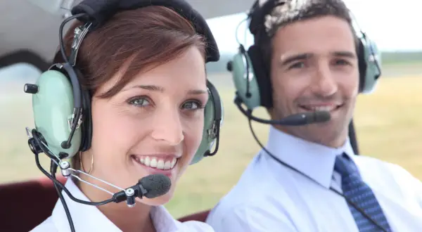 Para, czy pilot może mieć wadę wzroku? Dwoje ludzi w słuchawkach z mikrofonem w samolocie.