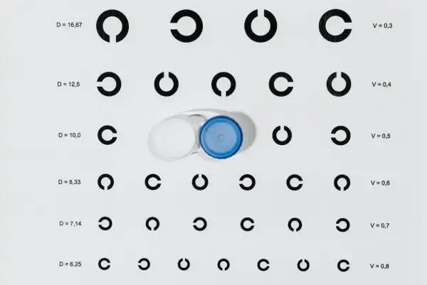 Tabela optometryczna z pierścieniami Landolta i pojemnikiem na soczewki kontaktowe.