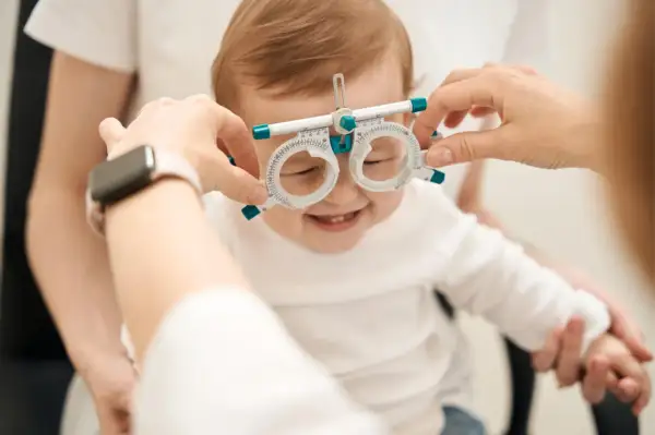 Uśmiechnięte niemowlę z oprawką optometryczną na nosie, jak widzi miesięczne dziecko.